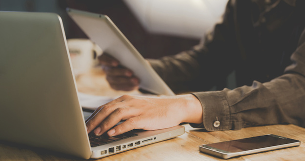 5 Options for Investing in Real Estate With Bad Credit Businessman working at office desk and signing a document, computers and paperwork all around, t
