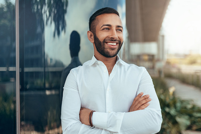 What One NYT Bestseller Says About Traps That Hold Ambitious People Back Portrait of a young confident smiling indian man with his arms crossed looking into the distance
