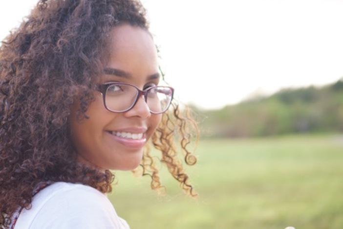 Why You Shouldn’t Worry About How Many Loans You Have in Real Estate dark curly haired pretty woman in glasses smiling outdoors