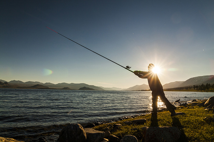 The Vital Question Investors Forget to Ask: Does Your Strategy Support Your Ideal Life? Silhouette of a fisherman at sunset. Fishing on mountain lake