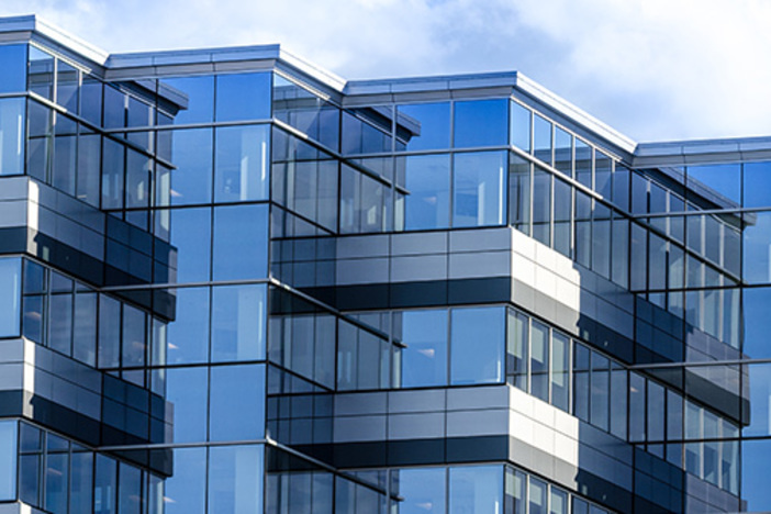 What’s the Best Type of Commercial Real Estate Property for Investors? mirrored glass office building set against cloudy sky