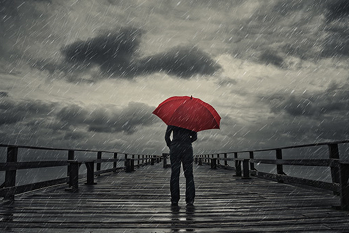 6 Ways to Prepare for the Next Market Crash A woman holds a red umbrella on a fishing pier during a storm.