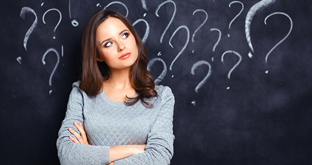 Think Cost Segregation Is Too Expensive? Here’s Why You’re Wrong young dark-haired woman in gray sweater standing in front of blackboard with questions drawn on it in white chalk