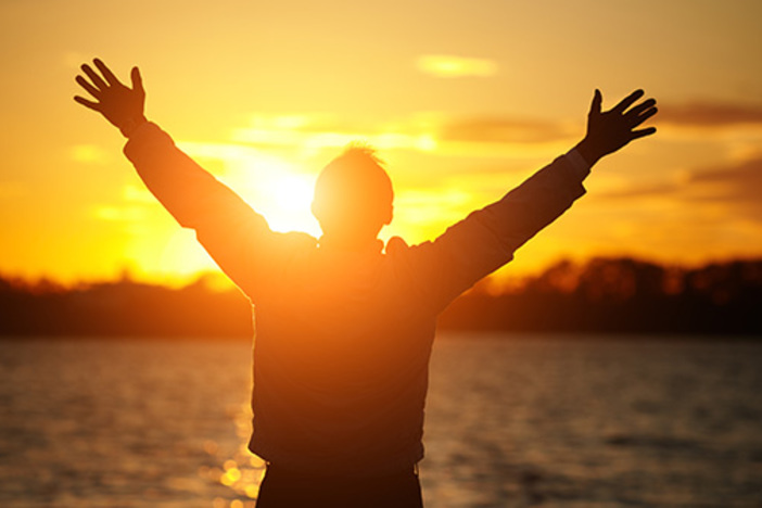 How to Retire From a $50,000 Job on Just $25,000 of Rental Cash Flow silhouette of man standing in front of water during sunset with hands stretched overhead symbolizing gratitude