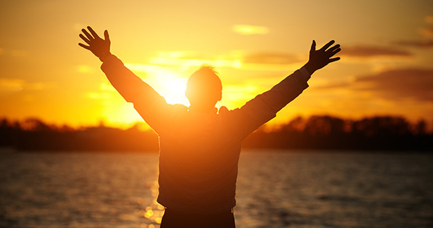 How to Retire From a $50,000 Job on Just $25,000 of Rental Cash Flow silhouette of man standing in front of water during sunset with hands stretched overhead symbolizing gratitude