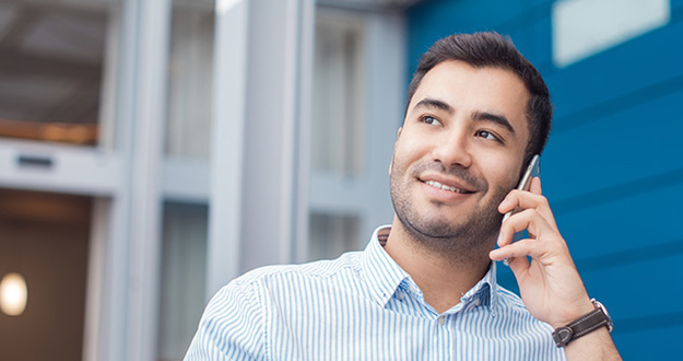 Owning Your Own Office Is Easier Than You Think Happy young man on phone, indoors - inside. Close up of businessman talking on mobile phone - smartphone. Comunicative friendly hispanic man