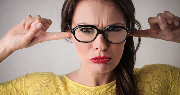 News Flash: Zillow Is NOT a Game-Changer in Real Estate close up of woman wearing red lipstick and glasses with smug expression and plugging ears