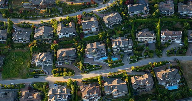 Why Is Getting Started in Real Estate So Hard?! (& How to Overcome 4 Common Barriers) Aerial view of the big luxury homes on the hill during a vibrant sunny summer day.