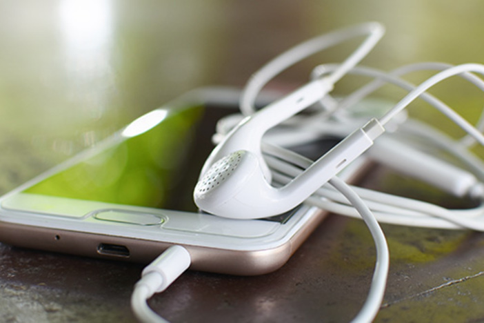 The 13 Best Real Estate & Personal Finance Podcasts Right Now Headphone and smart phone with soft light