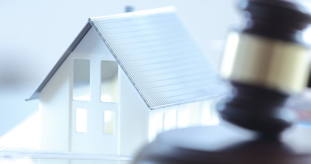 Legal Questions About Investing in Real Estate Across State Lines—Answered! Close up Conceptual White Miniature House on Top of the Table Beside Court Gavel.