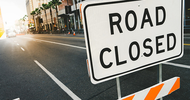 5 Roadblocks on the Path Toward Financial Freedom Road closed sign and traffice cone in the street. Traffic control sign road closed in the city. Road closed sign on Hollywood Boulevard.
