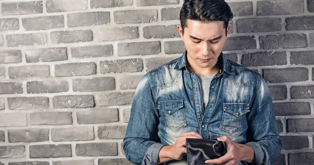 I Used a Hard Money Loan to Invest—Here’s What Happened man against gray brick background looking down into empty wallet