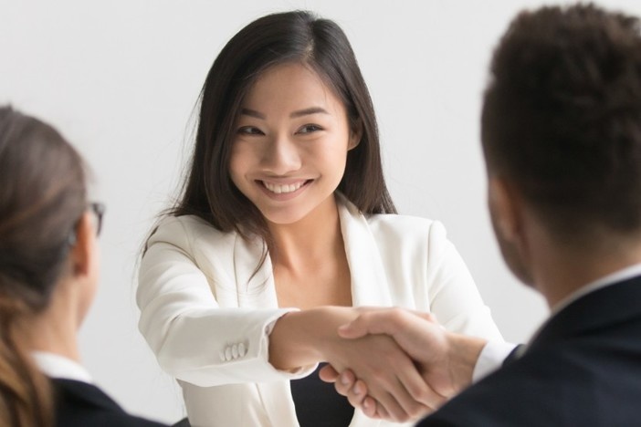 Real Estate Partnerships: A Powerful (& Profitable) Way to Start Out as an Investor three young business people sitting at desk two are shaking hands