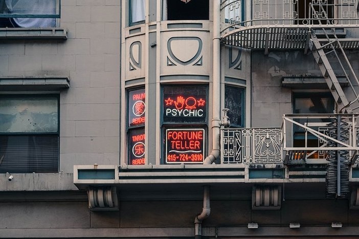 Where Is the Housing Market Headed in 2021? Top 10 Predictions From an Economic Expert tan mixed use building with neon sign advertising psychic and fortune telling
