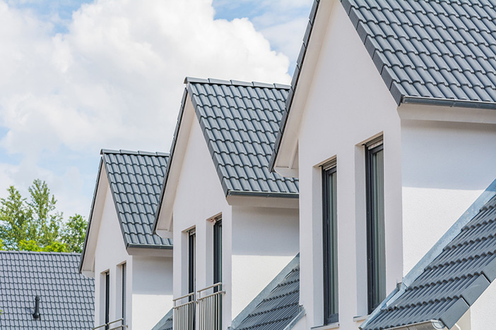 How I Bought a Fixer-Upper Fourplex for $1 Down: A BRRRR Case Study close up view of upper level windows and roofs on four row homes
