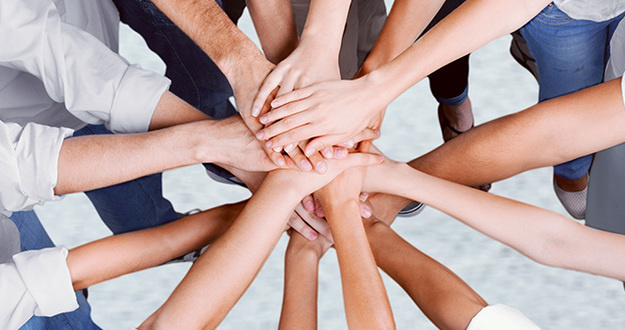 How to Hire Amazing Team Members for Every Real Estate Process—From Finding Deals to Renting Them Out closeup of hands piled on top of one another indicating teamwork