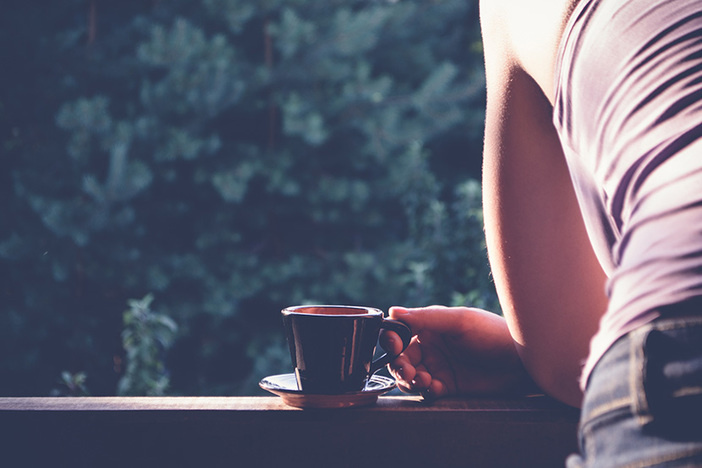 6 Steps to Improve Your Financial Situation (in a Way That Actually Lasts!) tight shot of woman leaning on deck rail drinking coffee overlooking backyard