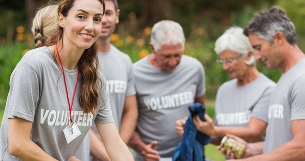 3 Ways Investors Can Give Back to Their Communities (& the Larger World) Happy volunteer looking at donation box
