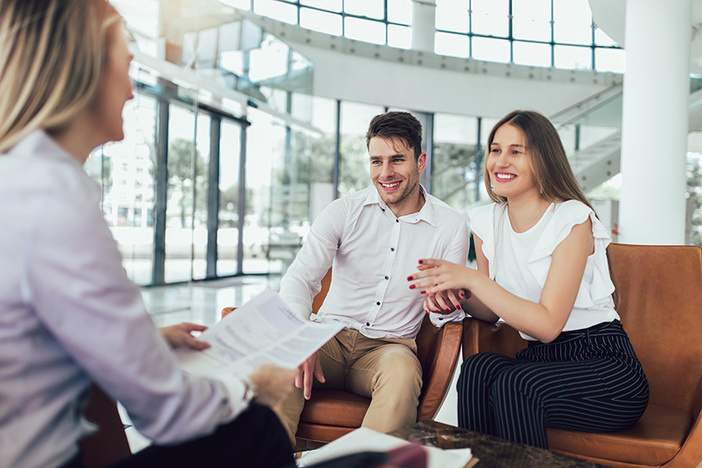 How Much Do Property Managers Charge? Here’s What Fees to Expect Financial advisor showing report to young couple for their investment. Salesman and positive couple talking about purchase. Happy couple consulting financial agent for loan.